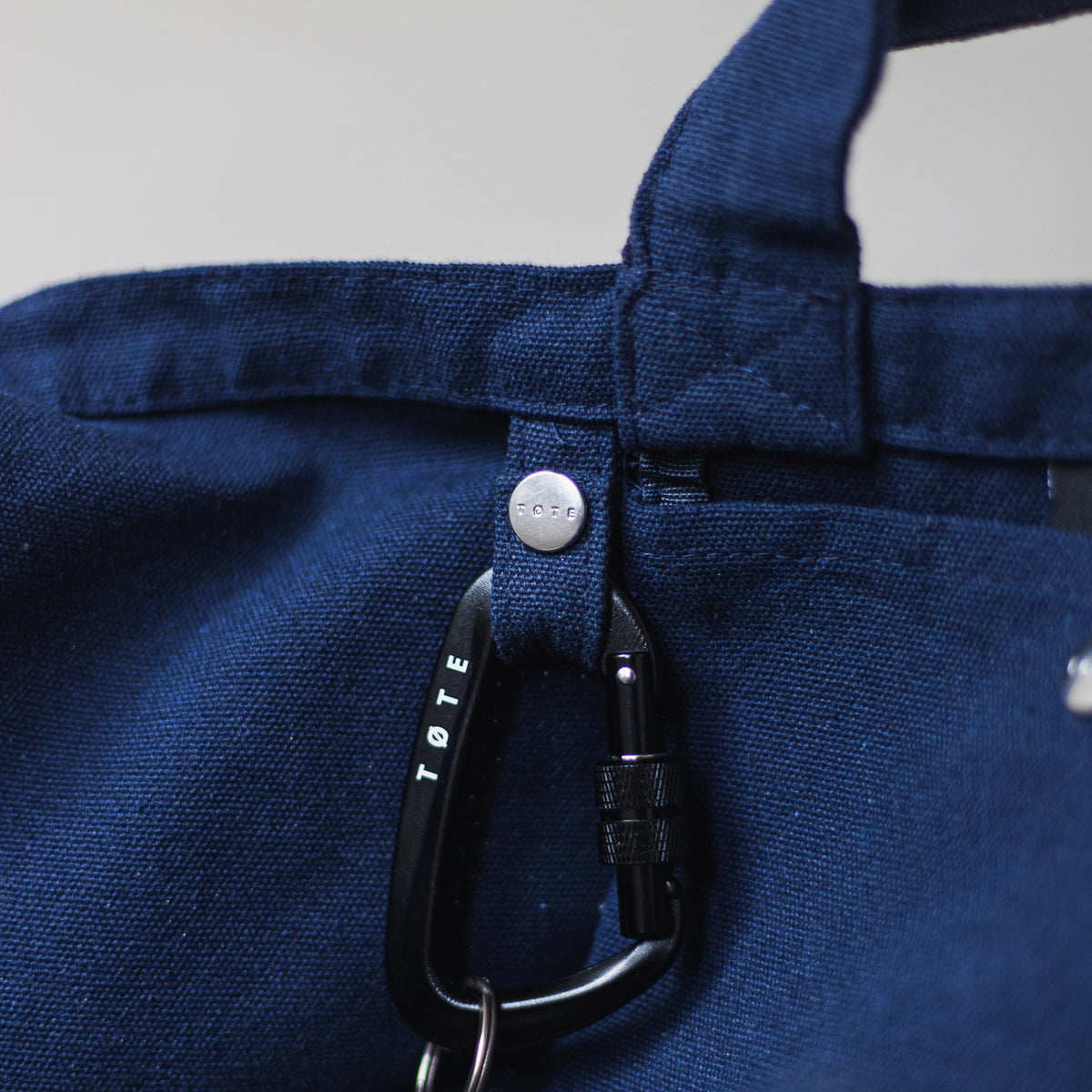 The keychain loop inside the Navy Blue TØTE Bag with The Carabiner clipped to it