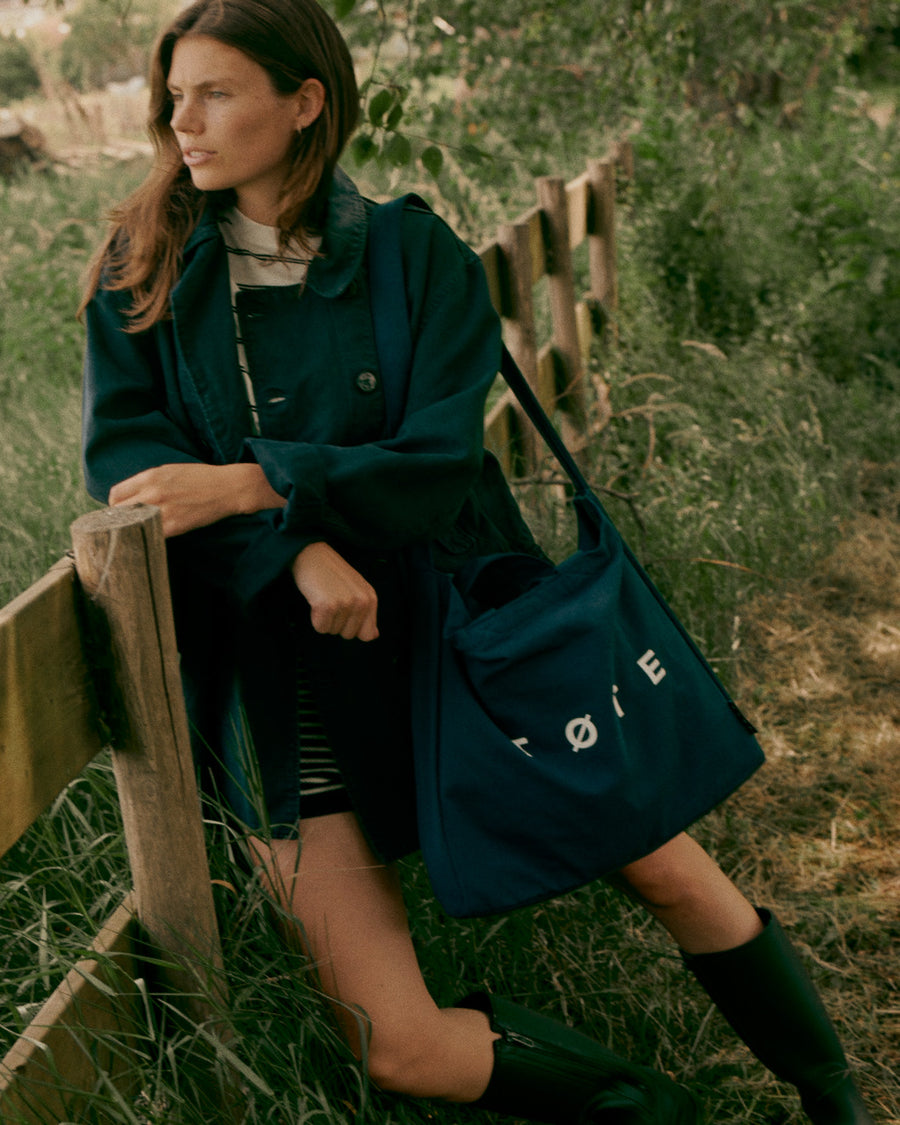 Navy Blue TØTE Bag beside a woman seated in a field