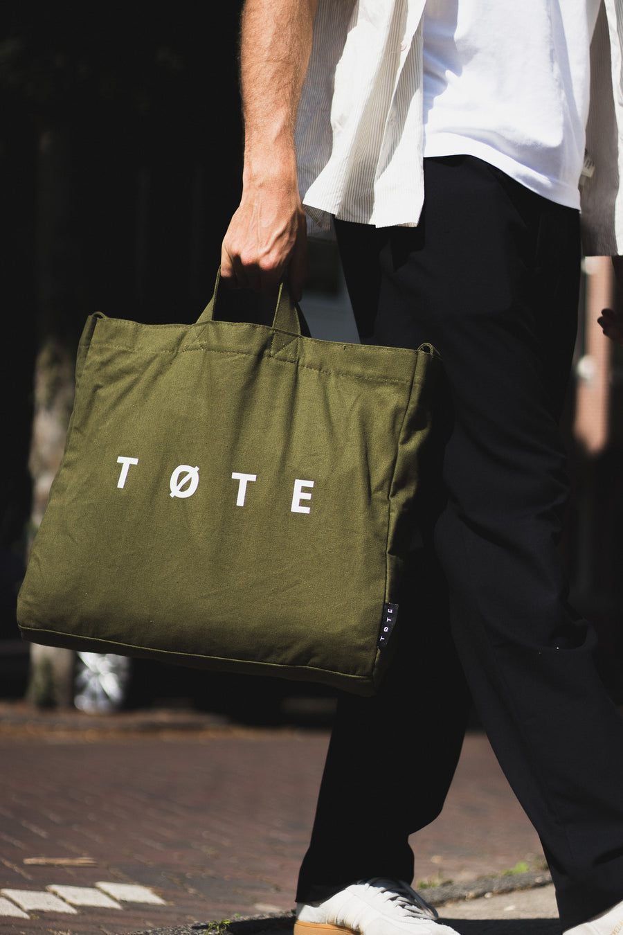 Khaki Green TØTE Bag carried by hand while walking