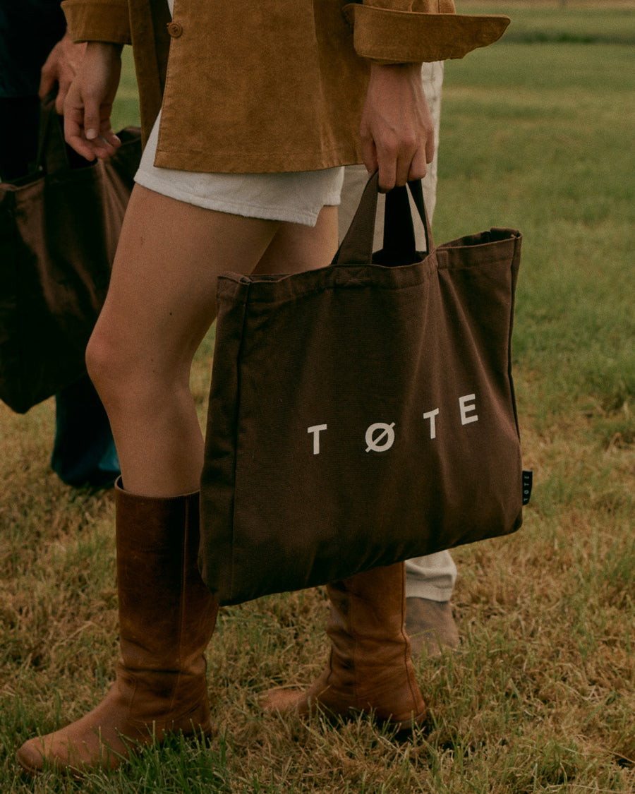 Khaki Green TØTE Bag carried by the handles in a field