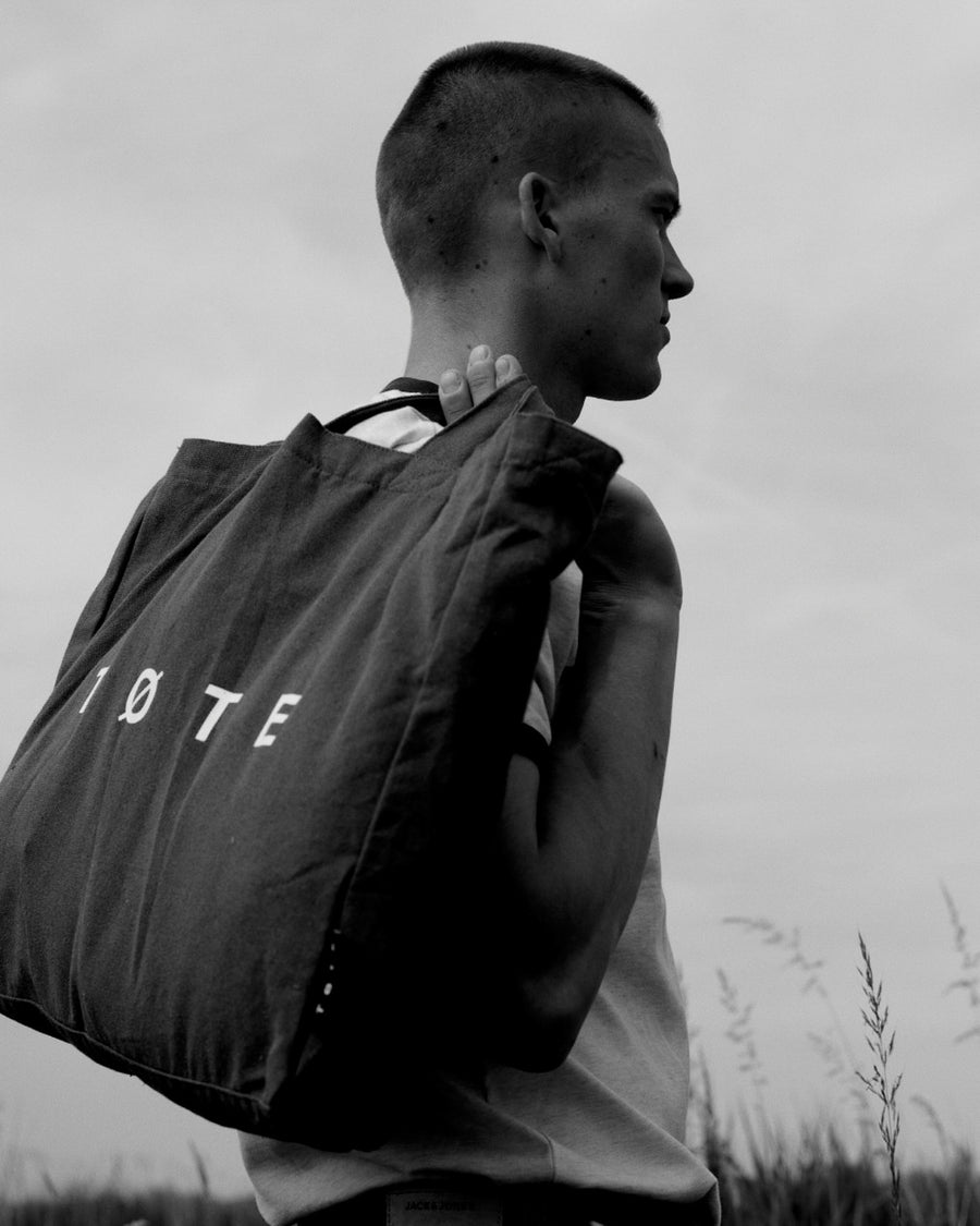 Black TØTE Bag over the shoulder in a summer field